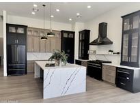 Modern kitchen with stainless steel appliances, light wood floors, island with white countertop and black base at 6931 E Teton Cir, Mesa, AZ 85207