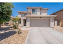 Two-story home featuring a neutral color scheme, two-car garage, desert landscaping, and tile roof at 9352 W Pioneer St, Tolleson, AZ 85353