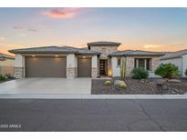 Beautiful home featuring a three-car garage, stone accents, and desert landscaping at 3020 N 165Th Ave, Goodyear, AZ 85395