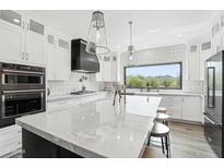 Bright, modern kitchen with white cabinets, marble counters, stainless steel appliances, and island seating at 38953 N 57Th Pl, Cave Creek, AZ 85331