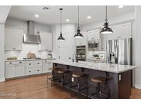 Modern kitchen featuring a large island, stainless steel appliances, white cabinets, and hardwood floors at 10154 E Bergeron Ave, Mesa, AZ 85212
