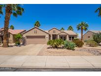 Charming single story home with desert landscaping, lush palms, and a two-car garage at 16280 W Desert Winds Dr, Surprise, AZ 85374