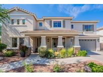Inviting two-story home featuring a covered porch with stone accents and a well-manicured front yard at 18868 E Mockingbird Dr, Queen Creek, AZ 85142