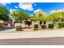 Charming desert home featuring a landscaped yard, attached garage, and a welcoming entrance with a wrought-iron gate at 26853 N 89Th Dr, Peoria, AZ 85383