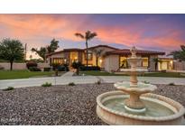 Elegant home featuring beautiful landscaping and fountain against a vibrant sunset backdrop at 5044 W Electra Ln, Glendale, AZ 85310