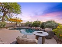 Backyard pool with a beautiful lounge area, complete with an umbrella and a fire pit, against a picturesque sky at 10623 E Acacia Dr, Scottsdale, AZ 85255