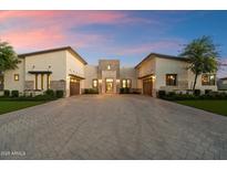 Expansive driveway leading to a luxury home with attached garages and stone accents under a beautiful sunset at 19917 E Natalie Way, Queen Creek, AZ 85142