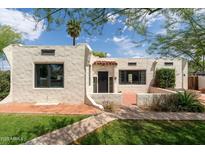 Charming home featuring stucco exterior, a red tile roof detail, black trimmed windows, and well-manicured front lawn at 356 W Roma Ave, Phoenix, AZ 85013