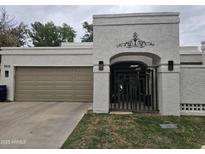 Charming single-story home features an attached garage, decorative gate, and well-maintained lawn at 8935 N 82Nd St, Scottsdale, AZ 85258