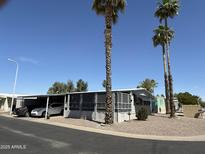 Charming mobile home featuring a covered parking area and mature palm trees at 9501 E Broadway Rd # 21, Mesa, AZ 85208