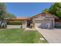 Charming home featuring a well-manicured lawn, desert landscaping, and a two-car garage at 1226 E Greenway Cir, Mesa, AZ 85203