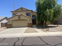 Charming two-story home with a tan stucco exterior, attached garage, landscaped yard, and inviting arched front door at 15897 N Gil Balcome St, Surprise, AZ 85374