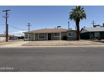 Charming single-story home with a brown roof, tidy landscaping, and a mature palm tree in the front yard at 5815 N 21St Ave, Phoenix, AZ 85015
