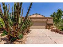 Beige home featuring a two-car garage and well-maintained desert landscaping, complete with various cacti and shrubbery at 630 E Jensen St # 102, Mesa, AZ 85203