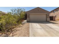 Tan single-Gathering home features a two-car garage and low maintenance desert landscaping in the front yard at 829 S 111Th Dr, Avondale, AZ 85323