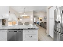 Open-concept kitchen with stone countertops, breakfast bar and stainless steel dishwasher at 8948 W Fargo Dr, Peoria, AZ 85382
