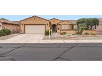 Inviting single-story home with desert landscaping, mature trees, and a well-kept lawn at 17009 W Eureka Springs Dr, Surprise, AZ 85387