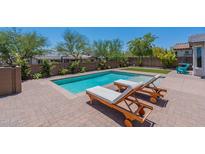 Backyard pool with chaise lounges on a brick patio surrounded by mature landscaping and a black fence at 2543 W Rabjohn Rd, Phoenix, AZ 85085