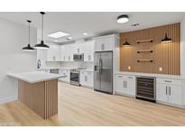 Bright, updated kitchen with white cabinets, stainless steel appliances, island with waterfall countertop, and decorative wooden accent wall at 3221 N 37Th St # 26, Phoenix, AZ 85018