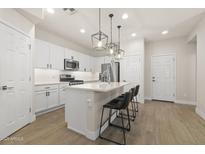 Well-lit modern kitchen boasts white cabinetry, stainless steel appliances, and a quartz countertop island with seating at 8343 E Irwin Ave, Mesa, AZ 85209