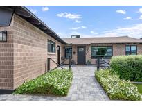 Charming brick home with a paved walkway, lush flower beds, and a welcoming black front door at 8425 E Bonnie Rose Ave, Scottsdale, AZ 85250