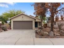 Charming single-story home featuring a well-manicured front yard and a two-car garage at 15715 W Cottonwood St, Surprise, AZ 85374