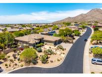 A beautiful aerial view of a desert home with lush landscaping and mountain views in the distance at 16562 N 109Th Way, Scottsdale, AZ 85255