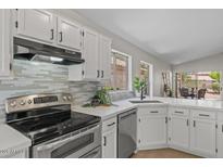 Bright kitchen featuring white cabinets, stainless steel appliances, and a stylish tile backsplash at 1761 E Countrywalk Ln, Chandler, AZ 85225