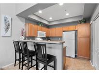 Modern kitchen with wood cabinets, stainless steel appliances, and breakfast bar seating at 2201 N Comanche Dr # 1094, Chandler, AZ 85224