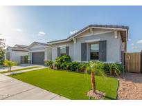 Charming single-story home featuring a landscaped front yard with artificial turf and a gray stucco exterior at 22858 E Silver Creek Ln, Queen Creek, AZ 85142