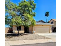 Tan single story home with desert landscaping, mature shade tree, and a two car garage at 23833 N 39Th N Ln, Glendale, AZ 85310