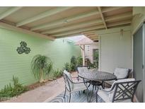 Charming patio area featuring a metal table set, plants and a colorful blue rug on brick pavers at 6626 N Majorca E Way, Phoenix, AZ 85016