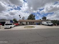 Charming single-story home with mature trees, green lawn, spacious driveway, and various vehicles parked in front at 6823 W Garfield St, Phoenix, AZ 85043