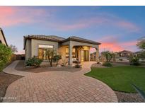 Beautiful backyard featuring a covered patio, green lawn, and mature landscaping at sunset at 8234 E Inca St, Mesa, AZ 85207