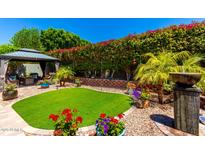 Beautiful backyard featuring a gazebo, manicured landscaping, and vibrant flowers at 1361 N Claiborne --, Mesa, AZ 85205