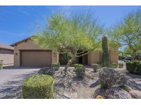 Tan home with a desert xeriscape front yard featuring various bushes, cactus and trees at 17303 N 98Th Pl, Scottsdale, AZ 85255