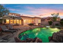 Inviting backyard with a sparkling pool, lounge chairs, and cozy fire pit under a beautiful sunset sky at 18500 N 95Th St, Scottsdale, AZ 85255