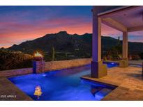 An inviting pool with a fire feature and a beautiful mountain backdrop at twilight at 37221 N Holiday Ln, Carefree, AZ 85377