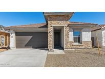Charming single-story home featuring stone accents, a brown garage door, and a low-maintenance front yard at 7718 W Minton St, Laveen, AZ 85339