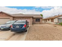 Cozy single-story brick home with a pink garage door, gravel front yard, and driveway parking at 9511 W Carol Ave, Peoria, AZ 85345