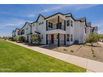 Beautiful townhouse with white exterior, black trim, well-manicured lawn, and sunny blue sky at 11300 N Casa Dega Dr # 1081, Surprise, AZ 85388