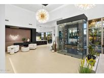 Bright living room with a glass-enclosed wine cellar, contemporary decor, and a view to the kitchen at 28754 N 107Th St, Scottsdale, AZ 85262