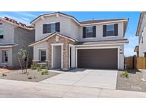 Charming two-story home featuring a stone entrance, dark shutters, and a spacious two-car garage at 7420 S 76Th Ln, Laveen, AZ 85339