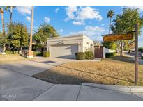 Beige home with a two-car garage and lush landscaping, complete with a beautiful lawn at 8405 E San Pedro Dr, Scottsdale, AZ 85258