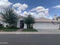 Charming single-story home featuring a well-manicured lawn, mature trees, and a spacious two-car garage at 3440 E Topeka Dr, Phoenix, AZ 85050