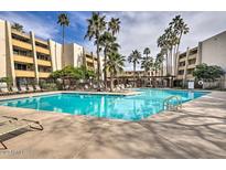 Enjoy the community pool surrounded by lounge chairs, palm trees and well maintained exterior of residential units at 7625 E Camelback Rd # A249, Scottsdale, AZ 85251