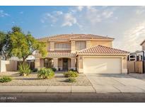 Charming two-story home featuring a tile roof, manicured landscaping, and an attached two-car garage at 10617 W Daley Ln, Peoria, AZ 85383