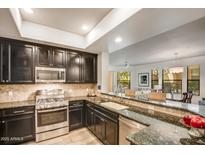 Modern kitchen featuring stainless steel appliances, granite countertops, and dark wood cabinetry at 7601 E Indian Bend Rd # 1050, Scottsdale, AZ 85250