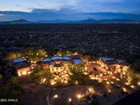 Expansive property at dusk with a Southwest design, desert landscaping and views of the city lights at 10092 E Troon North Dr, Scottsdale, AZ 85262