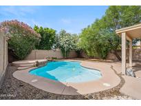 Inviting pool surrounded by lush landscaping, patio, and a rock waterfall feature at 2323 W Hunter Ct, Phoenix, AZ 85085